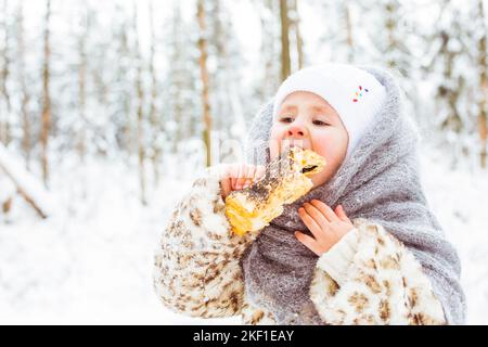 Ritratto invernale di bella ragazza sorridente bambino sulla passeggiata nella foresta innevata soleggiata Foto Stock