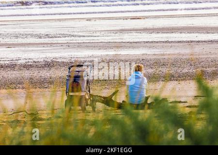 Una donna solitaria con un passeggino sulla spiaggia a Carradale Bay sulla penisola di Kintyre, Argyll & Bute, Scozia UK Foto Stock