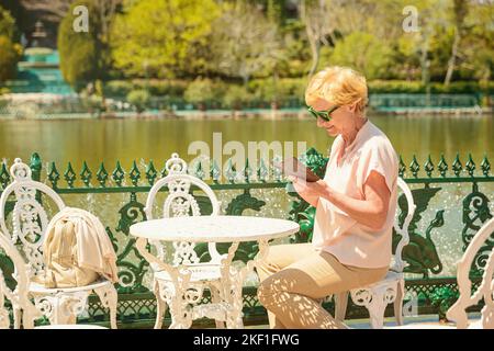 Donna adulta viaggiatore seduto da solo sulla terrazza della caffetteria Foto Stock