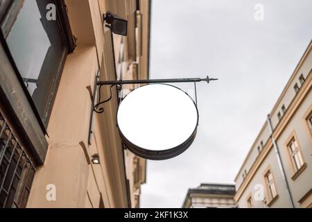 Fotografa il mockup bianco del cartello vintage del negozio di strada su un vecchio muro di mattoni gialli Foto Stock
