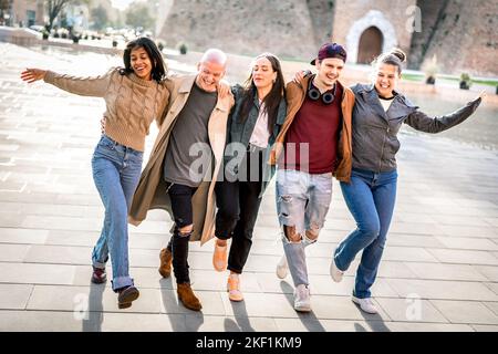 Amici internazionali alla moda che camminano nel centro della città giocando le mosse pazzesche divertenti - concetto freddo di stile di vita con i giovani allievi dell'università che si divertono intorno Foto Stock