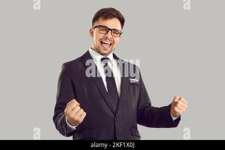Felice uomo d'affari eccitato in vestito e occhiali per celebrare il successo e divertirsi Foto Stock