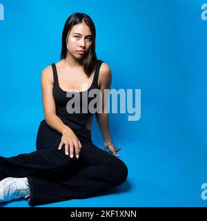 Multirazziale Teen Z-sitting piano Copy Space su sfondo blu Foto Stock