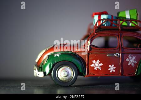 Una piccola auto di Natale in metallo retrò con una confezione regalo. Concetto di consegna dei regali Foto Stock