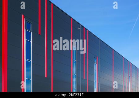 Facciata colorata con pannelli sandwich dal design moderno con strisce verticali rosse di un nuovo edificio industriale isolato termicamente con struttura in metallo Foto Stock