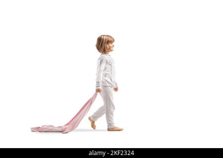 Profilo a tutta lunghezza girato di una bambina in pigiama camminare e tenere una coperta da ping isolato su sfondo bianco Foto Stock