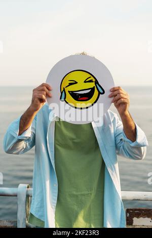 Ragazzo che nasconde il suo volto con una mano ridendo emotoji social network ridendo con lacrime - persone e mondo digitale nel concetto della vita reale Foto Stock