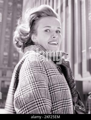 1960S GIOVANE DONNA ALLA MODA FREDDO BREEZY GIORNO CHE SI AGGRAPPA IL SUO CAPPOTTO GLEN PLAID CHIUSO AL COLLETTO CON LA MANO CON GUANTI CHE GUARDA MACCHINA FOTOGRAFICA - G5268 HAR001 HARS FELICE GIOIA LIFESTYLE SODDISFAZIONE FEMMINE HEALTHINESS COPIA SPAZIO SIGNORE PERSONE PLAID B&W INVERNO OCCHIO CONTATTO SOGNI BELLA FELICITÀ TESTA E SPALLE STILI ALLEGRI BREZZA ECCITAZIONE ORGOGLIO GLEN GLOVED SORRISI WEST COAST CITTÀ GIOIOSO ELEGANTE SOFFIATO DAL VENTO WINTERY BREEZY MODA GIOVANE DONNA ADULTA NERO E BIANCO CAUCASICA ETNICITÀ AGGRAPPANDO HAR001 VECCHIO STILE Foto Stock