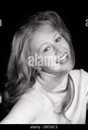 1970S BELLA GIOVANE DONNA SORRIDENTE INDOSSANDO UN MAGLIONE DOLCEVITA SORRIDENTE TESTA DI CAPELLI TOUSLED INDIETRO GUARDANDO VERSO LA MACCHINA FOTOGRAFICA - G8255 HAR001 HARS FEMMINE STUDIO SHOT SALUBRITÀ COPIA SPAZIO SIGNORE FAN PERSONE FIDUCIA B&W OCCHIO CONTATTO PIUTTOSTO FELICITÀ TESTA E SPALLE ALLEGRO BREZZA ECCITAZIONE SU SORRISI GIOIOSO ELEGANTE TEENAGED TOUSLED VENTOSO SOFFIATO BREEZY USCENTE GIOVANE DONNA ADULTA NERO E BIANCO ETNICITÀ CAUCASICA HAR001 DOLCEVITA VECCHIO STILE Foto Stock