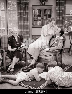 1930S FELICE FAMIGLIA ESTESA IN SOGGIORNO MADRE PADRE IN SEDIA DUE BAMBINI RAGAZZO E RAGAZZA SUL PAVIMENTO NONNA SUOCERA LETTURA - J2041 HAR001 HARS NONNA VECCHIO TEMPO NOSTALGIA FRATELLO VECCHIO MODA SORELLA 1 GIOVANE COMUNICAZIONE EQUILIBRIO FIGLI FELICE GIOIA LIFESTYLE SODDISFAZIONE CINQUE FEMMINE SPOSATE 5 FRATELLI STUDIO SHOT CONIUGE MARITI SALUBRITÀ HOME VITA COPIA SPAZIO AMICIZIA FULL-LENGTH MEZZA-LENGTH SIGNORE FIGLIE PERSONE ISPIRAZIONE MASCHI PREMUROSI GRANNY FRATELLI SORELLE SENIOR ADULTI B&W PARTNER SENIOR DONNA OBIETTIVI SUCCESSO FELICITÀ ALLEGRA PROTEZIONE PER IL TEMPO LIBERO SOGGIORNO ORGOGLIO DI FRATELLO Foto Stock