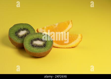 primo piano di kiwi e fette di arancia su sfondo giallo Foto Stock