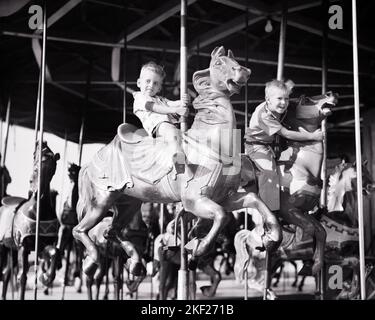 1950S DUE FRATELLI RAGAZZI A CAVALLO SUL CAROSELLO GIOSTRA ALLEGRO-GO-ROUND PARCO DIVERTIMENTI CARNIVAL RIDE - J5916 DEB001 HARS AVVENTURA DIVERTIMENTO ECCITAZIONE LOW ANGLE CAROSELLO ALLEGRO-GO-ROUND FRATELLO IMMAGINAZIONE A METÀ STRADA DEB001 COOPERAZIONE CRESCITA GIOVANI GIOSTRE PARCO DIVERTIMENTI NERO E BIANCO ETNICITÀ CAUCASICA VECCHIO STILE PARCO A TEMA Foto Stock