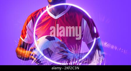 Sezione centrale del giocatore maschio afro-americano che tiene il pallone con il cerchio illuminato e le piante Foto Stock