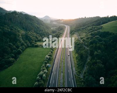 autostrada vista dall'aria da un drone al tramonto in controluce tra la vegetazione l'erba e gli alberi della foresta, ribadesella asturias Foto Stock