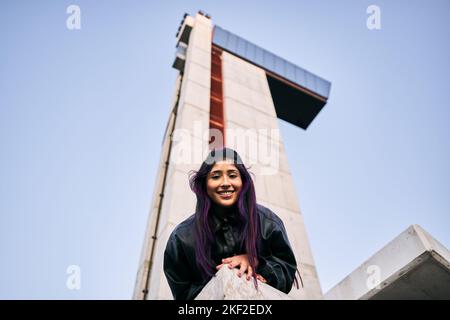 brunette latina ragazza in pelliccia giacca tinto capelli rosa sorridente alla fotocamera calma e rilassato sdraiato sul pavimento Foto Stock