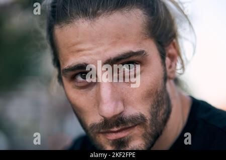 primo piano faccia caucasico ragazzo guardando in su con barba lunga capelli disheveled Foto Stock