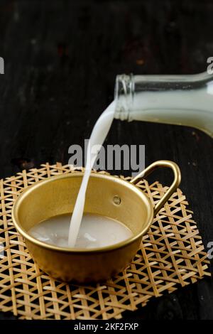 Versare il Makgeolli, l'alcol tradizionale coreano, il vino di riso coreano. Messa a fuoco selezionata Foto Stock