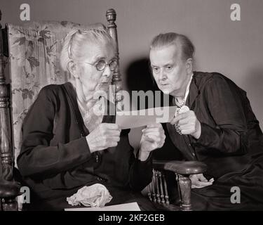 1940S DUE DONNE ANZIANE CHE GUARDANO AD UN CONTROLLO DI SICUREZZA SOCIALE CHE HA COMINCIATO ESSERE EMESSO IN GENNAIO 1940 - S2563 HAR001 HARS ANZIANO DONNA ANZIANO ANZIANO OLDSTER SCOPERTA AGLI ANZIANI SUPPORTO DI CONNESSIONE HA COMINCIATO ANZIANO DONNA PREVIDENZA SOCIALE NERO E BIANCO ETNICITÀ CAUCASICA HAR001 VECCHIO STILE Foto Stock