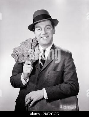 1950S 1960S RITRATTO SORRIDENTE UOMO D'AFFARI CON VALIGETTA CHE TIENE IL CAPPOTTO SUPERIORE SOPRA LA SUA SPALLA INDOSSANDO UN CAPPELLO CHE GUARDA LA MACCHINA FOTOGRAFICA - S2978 HAR001 HARS COPIA SPAZIO PERSONE DI MEZZA LUNGHEZZA MASCHI FIDUCIA B&W OCCHIO CONTATTO TUTA E CRAVATTA VENDITA ALLEGRO LE SUE OCCUPAZIONI SORRISI GIOIOSO STILE CRESCITA MEDIO-ADULTO MEDIO-ADULTO UOMO VENDITORI CAPPOTTO SUPERIORE NERO E BIANCO CAUCASICO ETNICITÀ HAR001 VECCHIO STILE Foto Stock