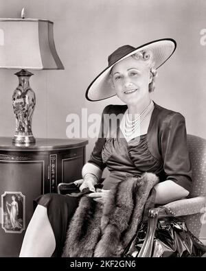 1940S ATTRAENTE DONNA DI MEZZA ETÀ CHE INDOSSA BIG HAT PEARL ABITO IN RASO CHE TIENE CODA FOX STOLE SEDUTA IN SEDIA GUARDANDO LA MACCHINA FOTOGRAFICA - S4230 HAR001 HARS RICCO PIACERE GIOIA LIFESTYLE DONNE ANZIANE STUDIO SHOT HOME VITA LUSSO COPIA SPAZIO FULL-LENGTH SIGNORE PERSONE SATIN FOX PENSIONAMENTO CODA FIDUCIA MEDIO-ETÀ B & W OCCHIO CONTATTO PENSIONATI FELICITÀ MEDIO-ETÀ DONNA STILI ALLEGRI RICCHEZZA SORRIDE ANZIANI DI ALTO LIVELLO STOLE LOVELY AFFLUENT GIOIOSO ELEGANTE ATTRAENTE ABITI BEN-TO-DO NERO E BIANCO CAUCASICO ETNICITÀ HAR001 VECCHIO STILE Foto Stock