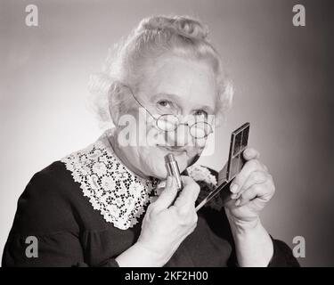 1950S DONNA ANZIANA GRANNY PERSONAGGIO METTERE SU ROSSETTO GUARDANDO LA FOTOCAMERA SORRIDENTE - S7845 DEB001 HARS FEMMINE NONNO STUDIO SHOT HOME VITA COPIA SPAZIO SIGNORE TRUCCO PERSONE VANITÀ CARATTERE GRANNY FIDUCIA SENIOR ADULTO B & W OCCHIO CONTATTO SENIOR DONNA SOGNI COSMETICI FELICITÀ VECCHIAIA OLDSTERS TESTA E SPALLE ALLEGRO OLDSTER INVECCHIAMENTO ECCITAZIONE ROSSETTO ORGOGLIO NONNE SORRIDE ANZIANI CONCETTUALE COMPATTO GIOIOSO DEB001 AGISM BIDDY GRIGIO CAPELLI NERI E BIANCHI CAUCASICI ETNICITÀ GRANDMA COLLETTO IN PIZZO VECCHIO STILE Foto Stock