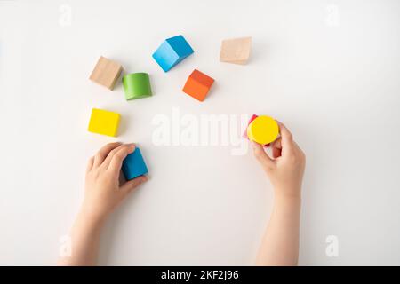 Colpo ad angolo alto di un bambino che gioca con colorati blocchi di giocattoli educativi sul tavolo presso la scuola materna o asilo. Il bambino si diverte mentre è impegnato in cr Foto Stock