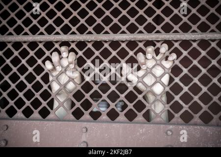 Primo piano di un uomo in mano di prigione dietro Hold barre di prigione in acciaio gabbia. Criminale delinquente bloccato in prigione. Foto Stock