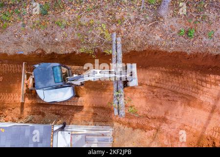 Il manipolatore del trattore viene utilizzato per il sollevamento dei tronchi per preparare il terreno per la costruzione di lavori in corso Foto Stock