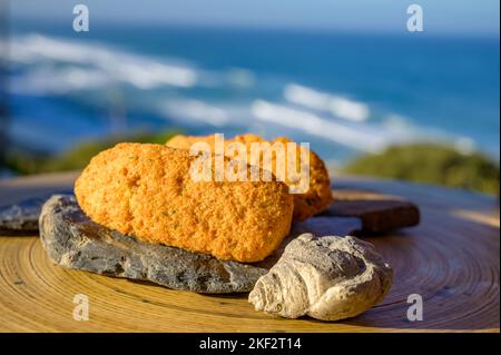 Coccodrillo pastais de bacalhau, spuntini tradizionali portoghesi serviti all'aperto con vista sull'oceano Atlantico blu vicino a Sintra nella zona di Lisbona, P Foto Stock