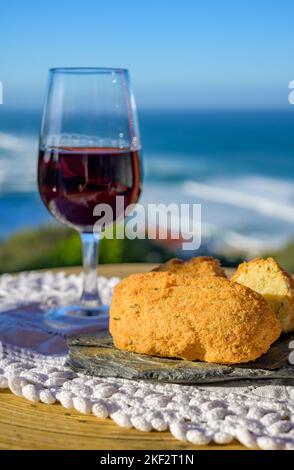 Abbinamento di cibo e bevande portoghesi, bicchiere di vino porto bruno e coccodrillo pastais de bacalhau, servito all'aperto con vista sul blu soleggiato Atla Foto Stock