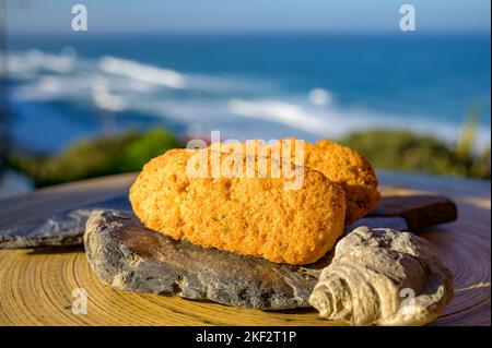 Coccodrillo pastais de bacalhau, spuntini tradizionali portoghesi serviti all'aperto con vista sull'oceano Atlantico blu vicino a Sintra nella zona di Lisbona, P Foto Stock