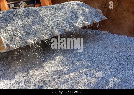 Durante i lavori di riparazione su strada in cantiere, l'escavatore con caricatore Bobcat è stato utilizzato per scaricare la pietra frantumata Foto Stock