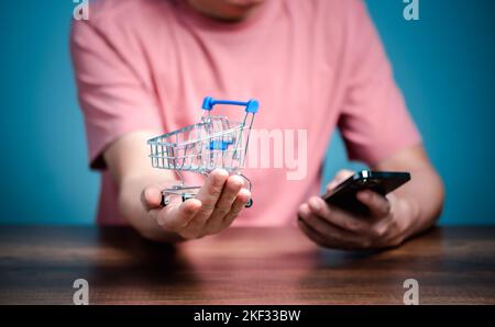 Shopping online con il carrello, l'uomo che utilizza il telefono cellulare acquistare cose sul negozio di pagine web. Foto Stock