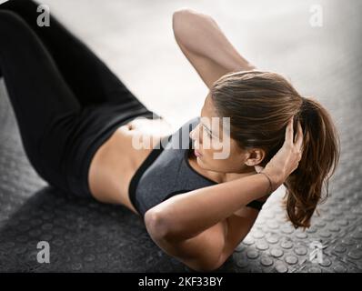 Lavorare i muscoli del nucleo. Una giovane donna che fa sit-up in palestra. Foto Stock