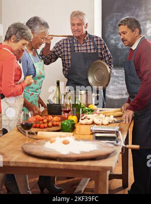 Cucinando insieme li avvicina. Un gruppo di anziani che cucinano nella cucina. Foto Stock