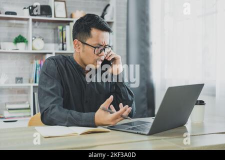 Uomo d'affari freelance che chiama su uno smartphone mentre lavora con un computer portatile seriamente stress depressione, uomo d'affari telefono cellulare che chiama con il busto Foto Stock