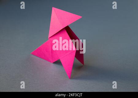 Carta rosa gallina origami isolato su uno sfondo bianco grigio. Cocotte en papier Foto Stock