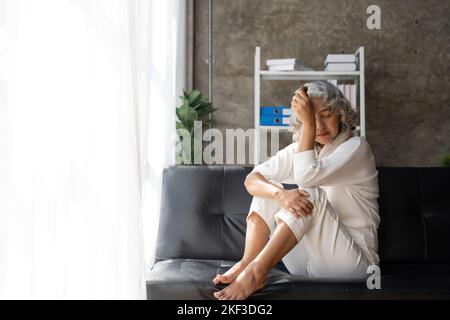 Triste stanco malato solo deluso anziana caucasica nonna anziana seduta sul divano letto, sensazione di nostalgia, dolore, scomparsa Foto Stock