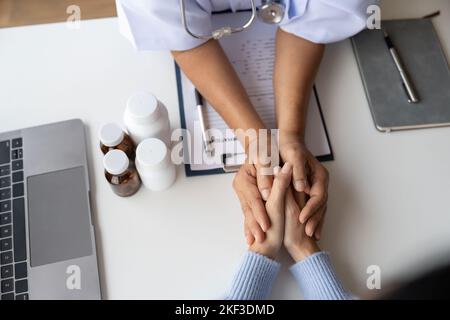 Dottore che dà speranza. Primo piano immagine di una giovane medico femminile che si appoggia in avanti a una donna anziana sorridente che tiene la mano nelle palme. Donna custode Foto Stock