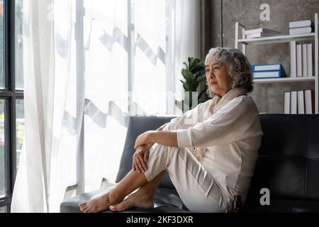 Triste stanco malato solo deluso anziana caucasica nonna anziana seduta sul divano letto, sensazione di nostalgia, dolore, scomparsa Foto Stock