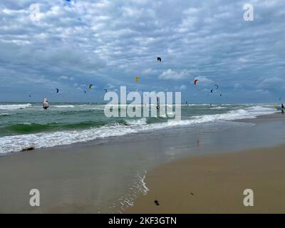 Surfista e Kite Surfer in una giornata ventosa e soleggiata sulla spiaggia del mare del nord Foto Stock