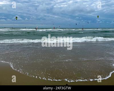 Surfista e Kite Surfer in una giornata ventosa e soleggiata sulla spiaggia del mare del nord Foto Stock