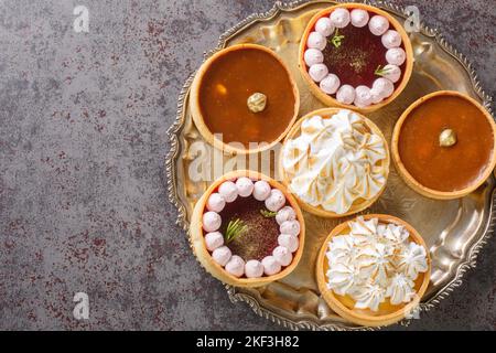 Deliziose tartine di dolci gourmet per la vacanza con meringa e cagliata di limone, cagliata di lamponi, noci e cioccolato primo piano sul tavolo. Orizzontale t Foto Stock