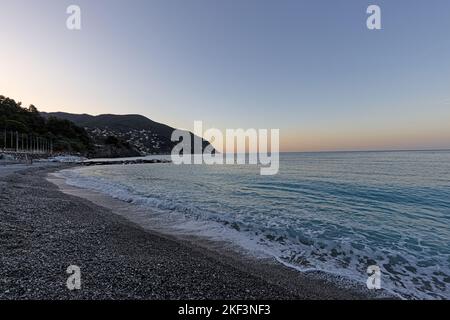 Vista sulla spiaggia di ciottoli di Moneglia sulla costa ligure durante il tramonto estivo Foto Stock