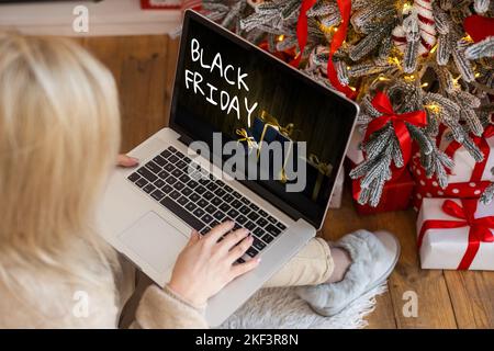 Concetto di shopping del Black Friday scritto sullo schermo nero del notebook contro lo sfondo sfocato delle luci di natale Foto Stock