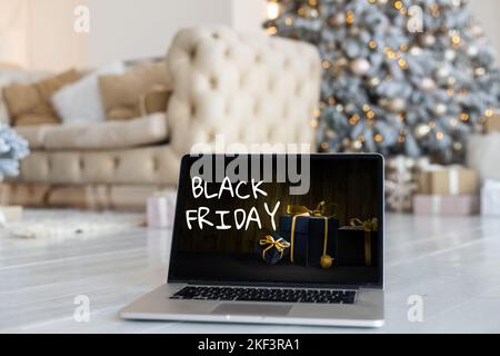 Concetto di shopping del Black Friday scritto sullo schermo nero del notebook contro lo sfondo sfocato delle luci di natale Foto Stock