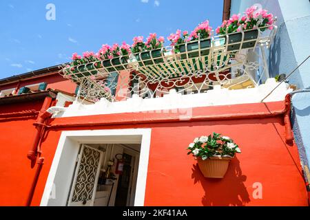 Vasi di fiori sul balcone e le pareti della casa rossa colorata architettura a Burano Isola, Venezia, Italia Foto Stock