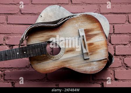 Vecchia chitarra di legno sulla parete. Chitarra antica senza archi Foto Stock