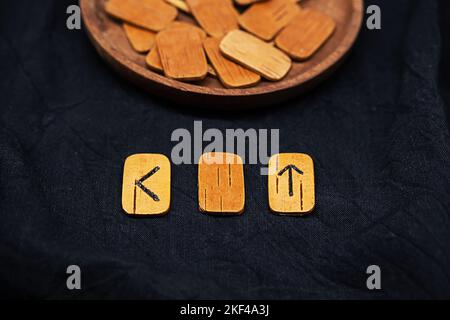 Rune di legno fatte a mano su tessuto nero. Cumulo di rune scandinave per divinazione, primo piano. Foto Stock