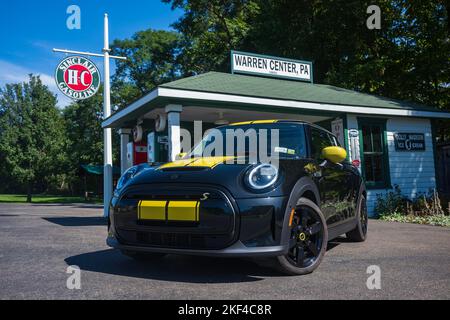 Warren Center, PA, USA - 24 settembre 2022: Un mini Cooper se 2023 nero e giallo, un veicolo elettrico, è fotografato vicino ad una stazione di benzina vintage locate Foto Stock